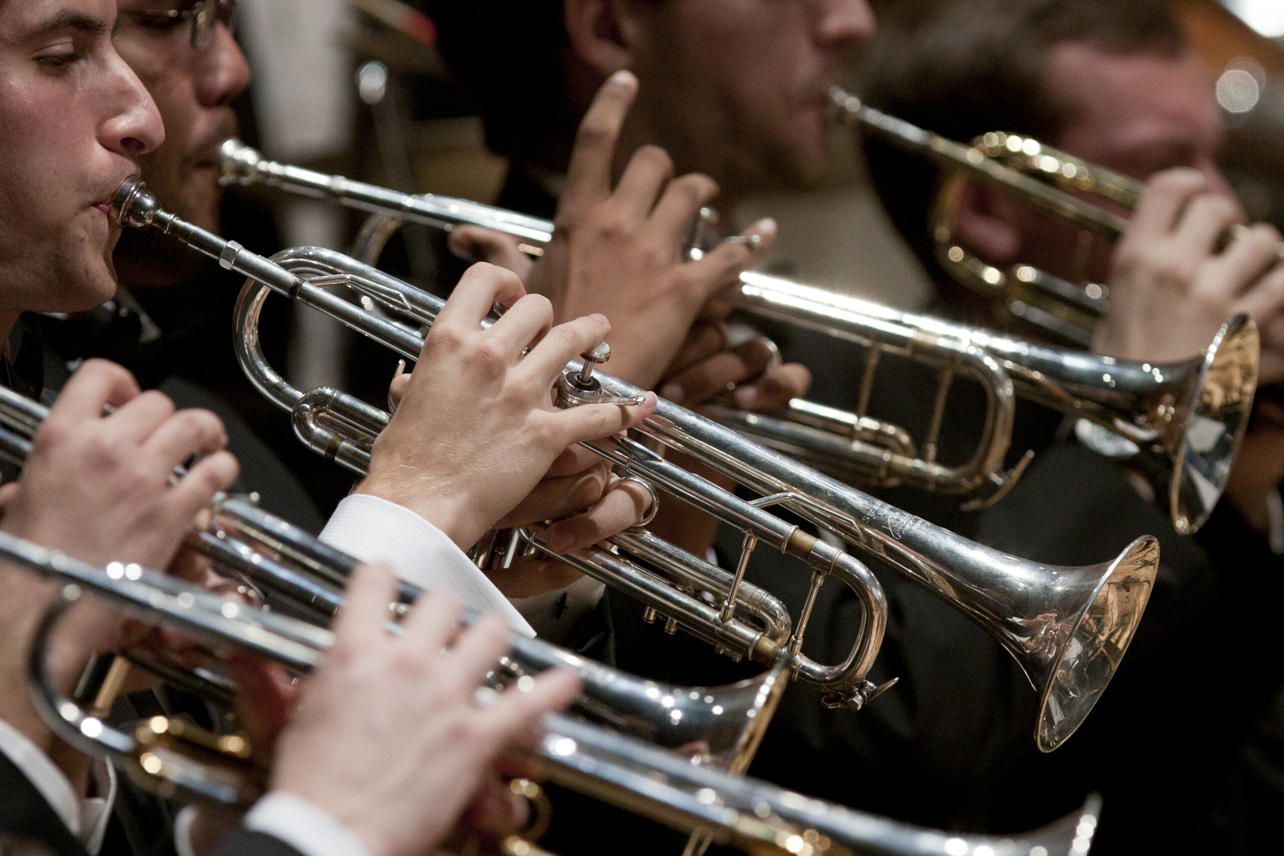 Students perform brass instruments on stage.