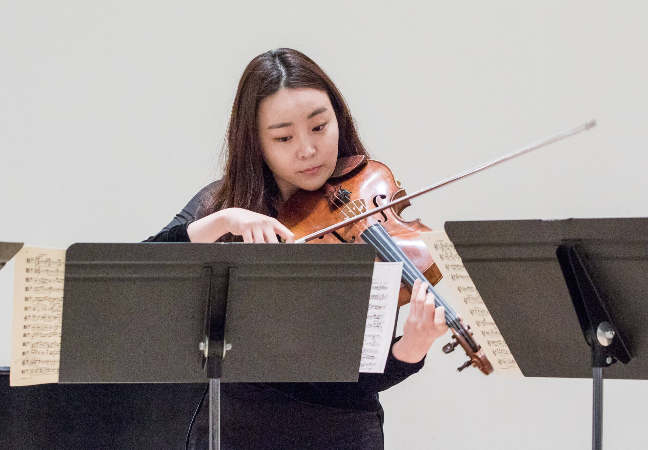 A student plays the violin in front of a music stand